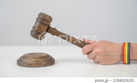 Judge with rainbow bracelet hits gavel.  126682620