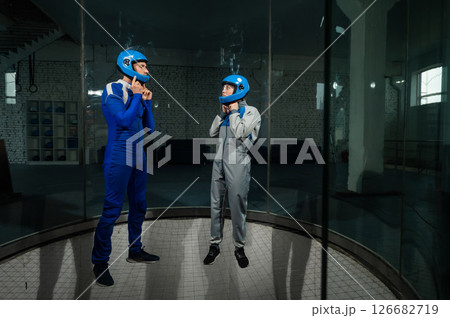 A male instructor teaches a woman how to fly in a wind tunnel. Free fall simulator. A male instructor teaches a woman how to fly in a wind tunnel. Free fall simulator. 126682719