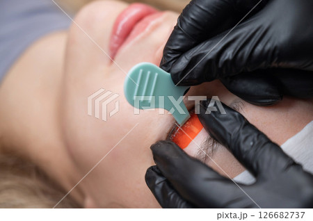 Caucasian woman undergoing eyelash lamination procedure.  126682737