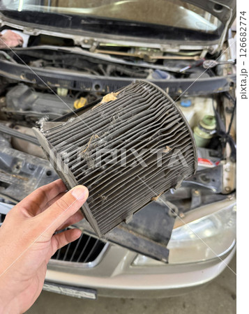 A dirty cabin air filter is replaced in a car. A dirty cabin air filter is replaced in a car. 126682774