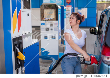 Woman refueling car with gasoline at self-service gas station. 126682831