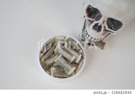 Skull Chewing Tobacco on a White Table. 126682848