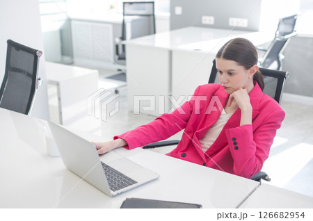 Caucasian business woman in fuchsia jacket working at computer.  126682954