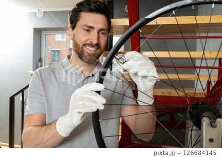 Mechanic in white gloves holding bicycle wheel 126684145