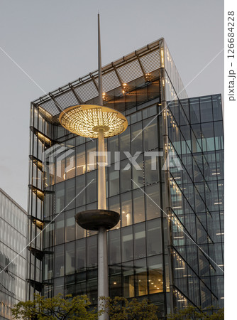 View of light pole in front of glass modern building on the Southbank after sunset in City of London. 126684228
