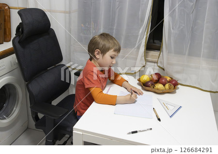 Young student doing homework at home with fruits on the table 126684291
