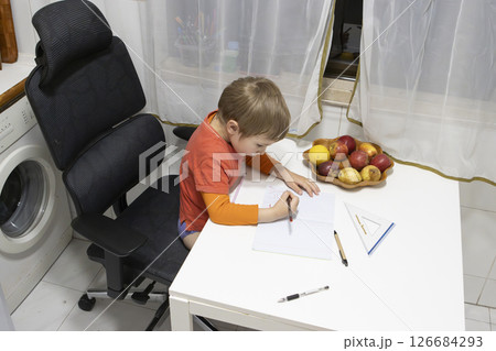 Preschooler drawing on notebook at home, sitting on ergonomic chair 126684293