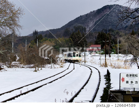 雪景色と電車が近づいて来る田舎の風景 126684589
