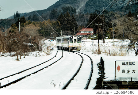 雪景色と電車が近づいて来る田舎の風景 126684590