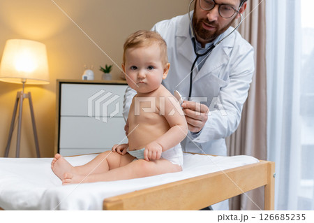 Doctor examining a cute little patient and looking concentrated Doctor examining a cute little patient and looking concentrated 126685235