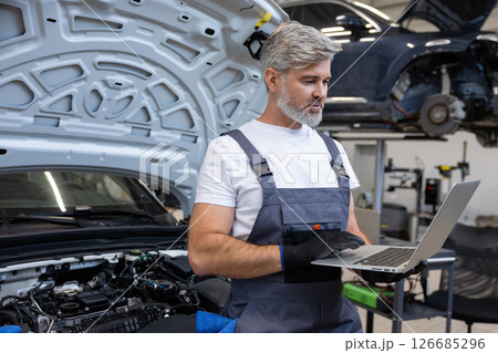 Mechanic performing diagnostics with laptop 126685296