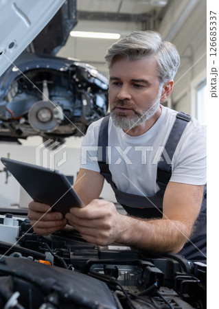 Mechanic performing diagnostics with tablet Mechanic performing diagnostics with tablet 126685337