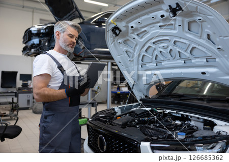 Mechanic performing diagnostics with tablet Mechanic performing diagnostics with tablet 126685362