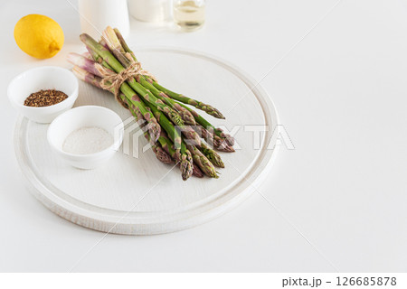 Fresh asparagus shoots with spices and lemon on white table. Top view 126685878