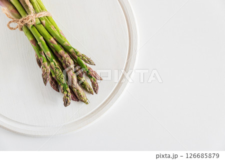 Fresh asparagus tied bundle on white table. Top view 126685879