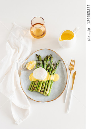 Poached egg with grilled asparagus and hollandaise sauce on white table. Top view 126685885