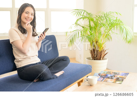 ソファーに座ってスマホを操作する女性 ソファーに座ってスマホを操作する女性 126686605