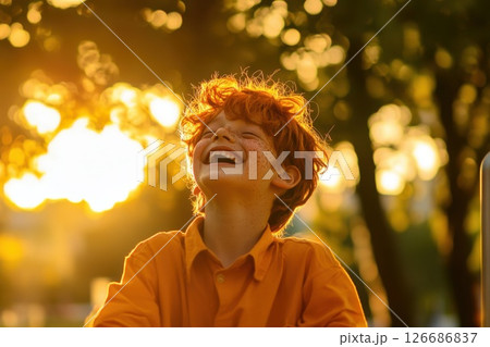 Joyful laughter of a teenage boy with freckles in a sunlit park on a warm day 126686837