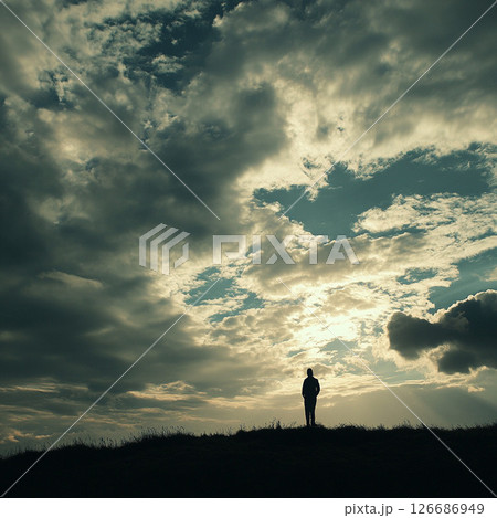 雲に包まれた空の下で立ち尽くす人物 126686949