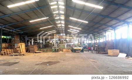 plywood processing plant showcasing Industrial Warehouse Interior with Stacks of Materials and Machinery, warehouse featuring industrial equipment, materials, and wooden pallets 126686992