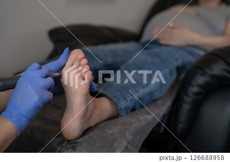 Pregnant woman on a hardware pedicure procedure in a beauty salon. Pregnant woman on a hardware pedicure procedure in a beauty salon. 126688958