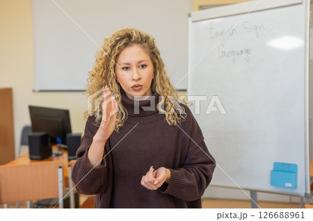 Caucasian female teacher communicates in Russian sign language with students. Caucasian female teacher communicates in Russian sign language with students. 126688961