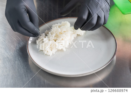 The chef puts boiled rice on a plate.  126688974