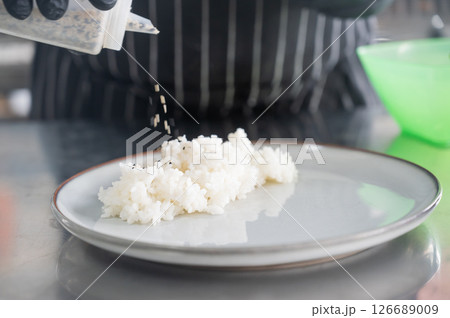 The chef puts boiled rice on a plate. The chef puts boiled rice on a plate. 126689009