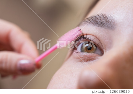 Caucasian woman brushing her eyelashes after lamination.  126689039