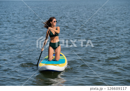 Caucasian woman riding a SUP board on the lake. Summer sport. Caucasian woman riding a SUP board on the lake. Summer sport. 126689117