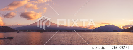 Panoramic sunset view over Lake Kawaguchi, where Mount Fuji silhouette stands against a golden sky 126689271