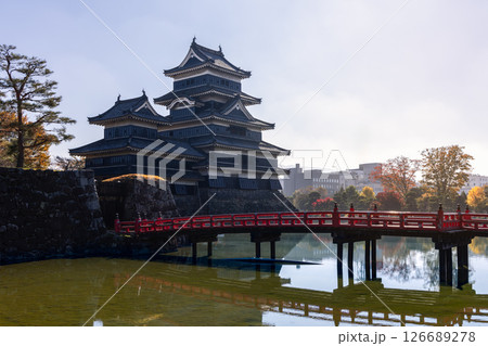Matsumoto Castle and its red bridge reflected in the still moat water, surrounded by autumn foliage Matsumoto Castle and its red bridge reflected in the still moat water, surrounded by autumn foliage 126689278