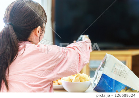 スナック菓子を食べながらテレビを見る女性 スナック菓子を食べながらテレビを見る女性 126689324