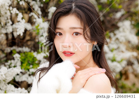 白い服着た若い女性が雪柳の花の周りでのんびりする 126689431