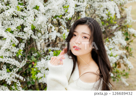 白い服着た若い女性が雪柳の花の周りでのんびりする 126689432