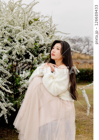 白い服着た若い女性が雪柳の花の周りでのんびりする 126689433