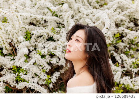 白い服着た若い女性が雪柳の花の周りでのんびりする 126689435