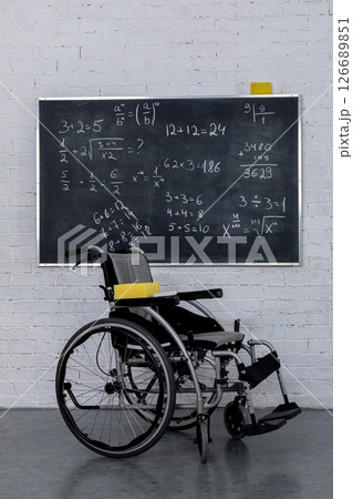 An Empty Wheelchair Positioned Next to a Black Chalkboard in a Modern Educational Classroom An Empty Wheelchair Positioned Next to a Black Chalkboard in a Modern Educational Classroom 126689851