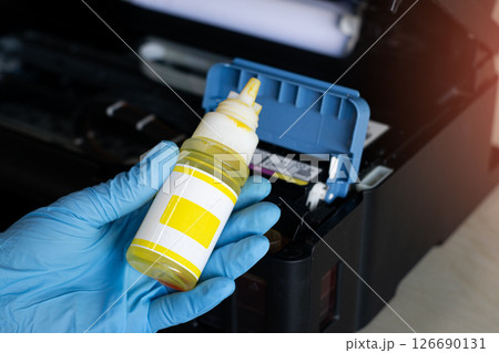 Side view of technician filling printer with ink. Side view of technician filling printer with ink. 126690131