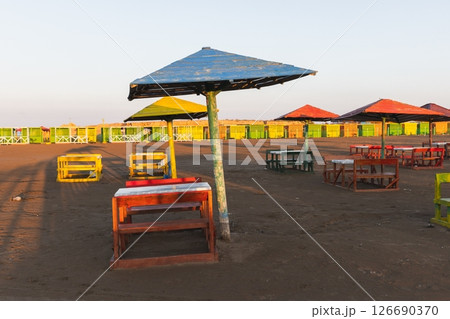 Vibrant wooden shelters and seating arrangements on a sandy beach 126690370
