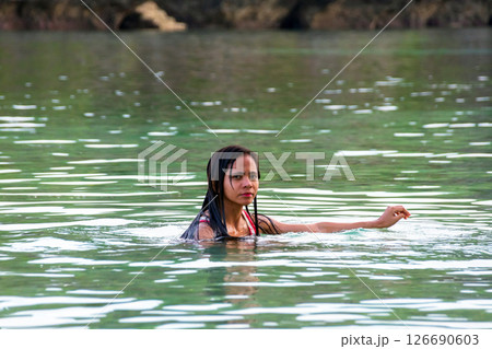 Young asian woman in swimsuit standing in tropical river with rocks behind 126690603