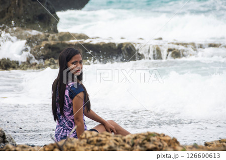 Woman smiling as ocean wave crashes dramatically behind her Woman smiling as ocean wave crashes dramatically behind her 126690613