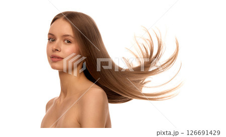 Portrait of woman with long shiny hair flying sideways in motion, showing clean skin, natural makeup against white studio background. 126691429