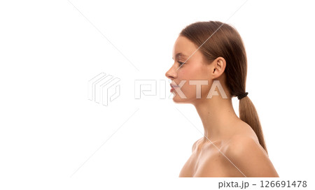 Side view of elegant young woman with tied back hair, straight profile, clean skin and relaxed posture with visible shoulders Side view of elegant young woman with tied back hair, straight profile, clean skin and relaxed posture with visible shoulders 126691478