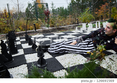 A vibrant chess scene with players in colorful attire set in a stunning natural landscape A vibrant chess scene with players in colorful attire set in a stunning natural landscape 126691569