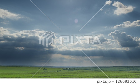 The tranquil sky stretches above the lush, green fields, creating a breathtaking view of nature Time lapse. 126692610