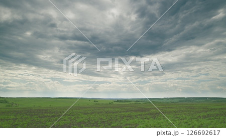 A Serene Overcast Landscape Featuring Expansive Lush Green Fields Under Dramatic Clouds Time lapse. A Serene Overcast Landscape Featuring Expansive Lush Green Fields Under Dramatic Clouds Time lapse. 126692617