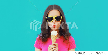 Summer portrait of happy young woman eating ice cream on blue background 126692748