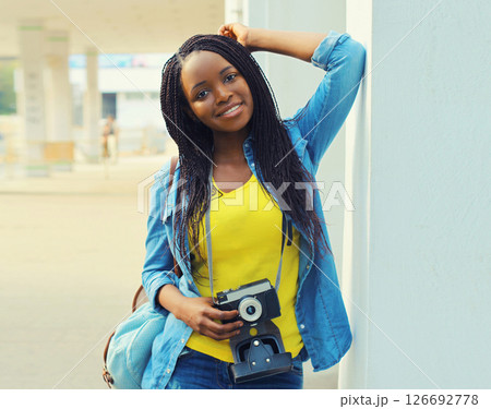 Summer portrait of happy smiling young woman photographer with film camera wearing summer straw hat 126692778