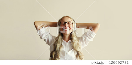 Happy smiling mature relaxing woman enjoying listening to music with headphones at home Happy smiling mature relaxing woman enjoying listening to music with headphones at home 126692781